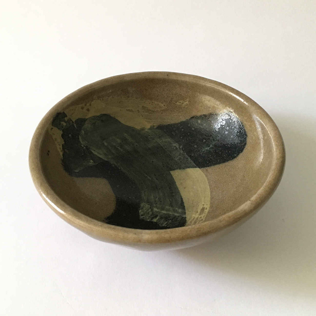 A studio pottery bowl with brush painting by Heidi Kippenberg. This ceramic in the colours brown, black, yellow is painted in the style of Tachism.