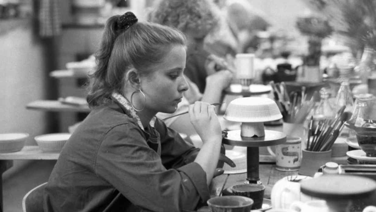 Hier findet das Keramik Bemalen in einer Keramikwerkstatt statt, in der eine Mitarbeiterin eine Schüssel aus Keramik bemalt.