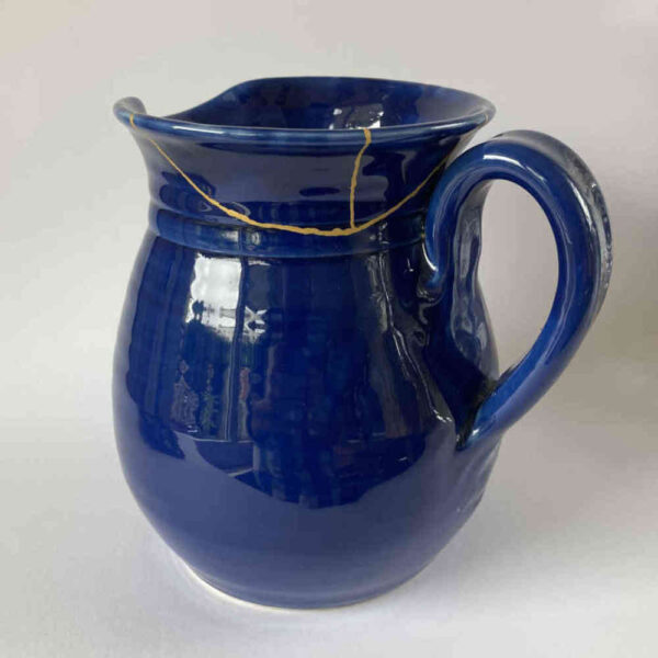 Réparation de céramique à l'aide de la technique Kintsugi avec de l'or sur une cruche en céramique.