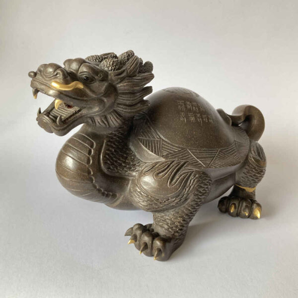 Réparation de céramique à l'aide de la technique Kintsugi à l'or sur une figurine de dragon - vue latérale.