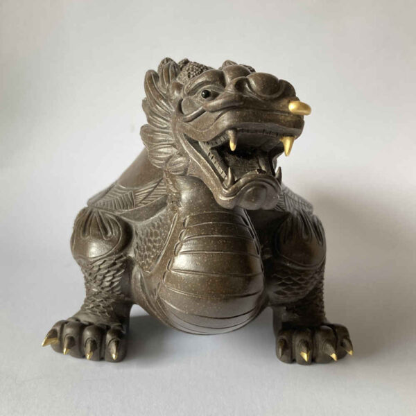 Réparation de céramique à l'aide de la technique Kintsugi à l'or sur une figurine de dragon - vue de face.