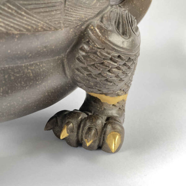 Réparation de céramique à l'aide de la technique Kintsugi à l'or sur une figurine de dragon - vue détaillée du pied.