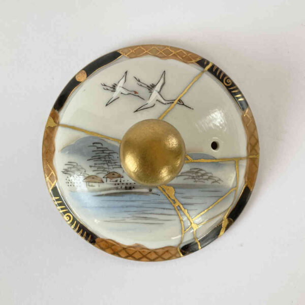 Réparation d'une céramique à l'aide de la technique Kintsugi à l'or sur un couvercle en porcelaine.