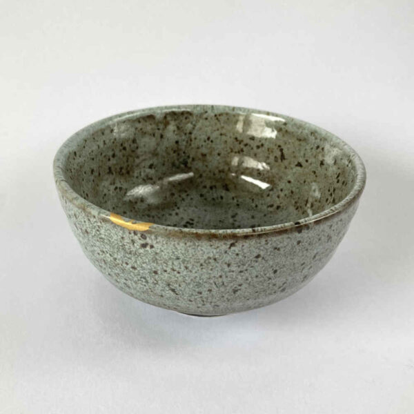 Riparazione di ceramiche con la tecnica Kintsugi con oro su scheggiatura del bordo di una ciotola.