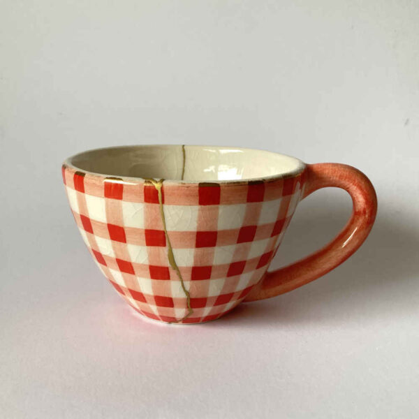 Riparazione di ceramiche con la tecnica di riparazione Kintsugi con oro su tazza.